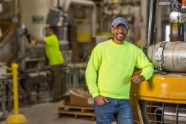 A male employee at a Saint-Gobain North America plant smiles, proud of his successful path in manufacturing and operations jobs.