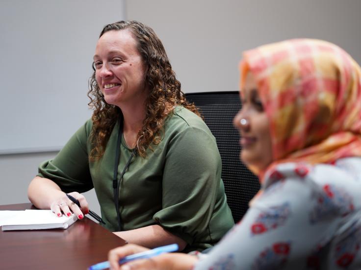 Two women seated at the corner of a conference table.