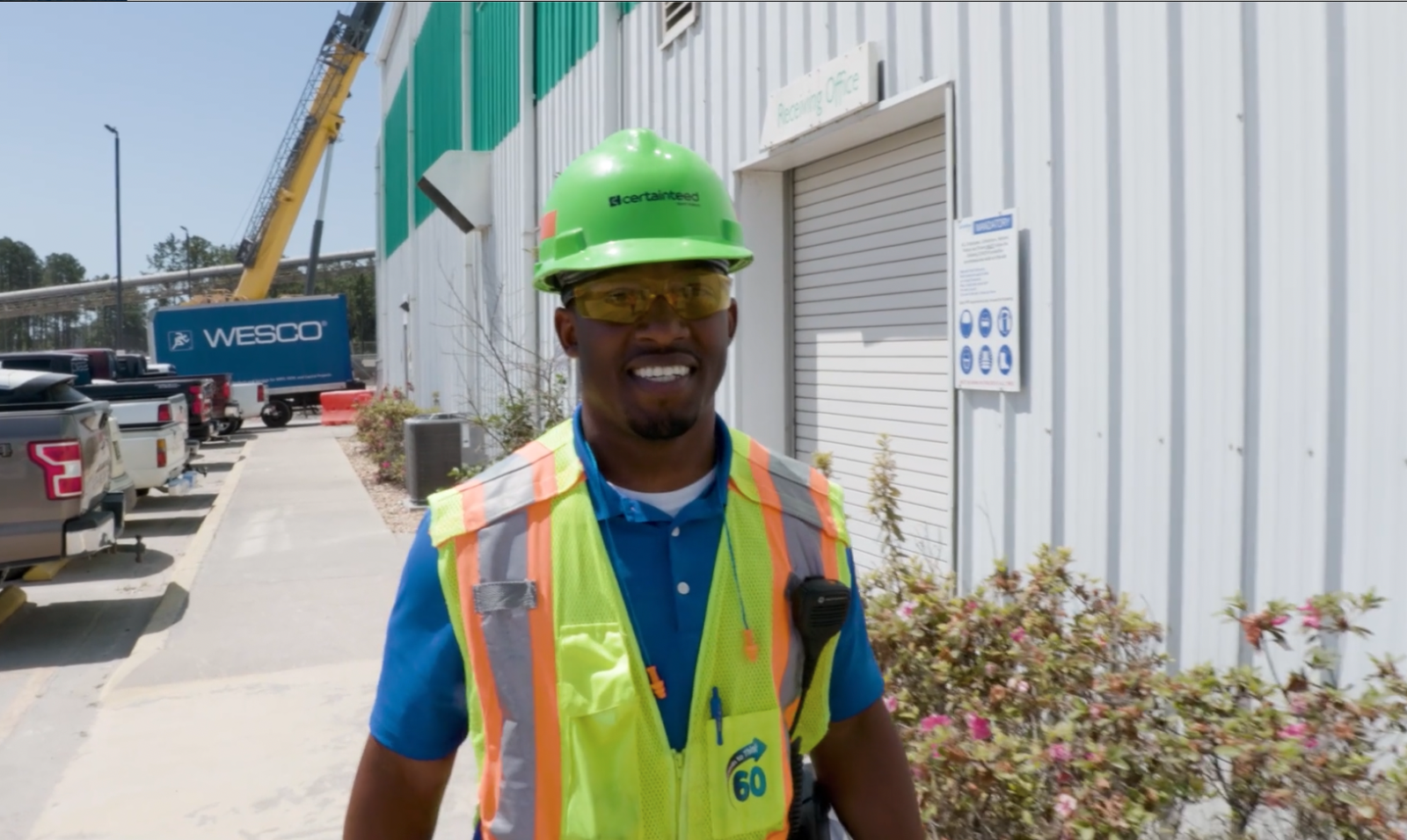 A man in yellow safety gear walks outside the manufacturing plant
