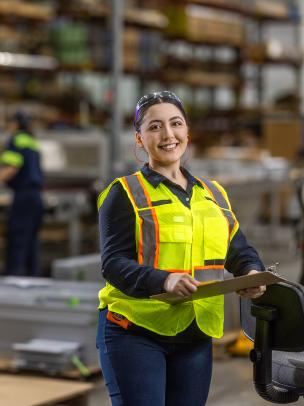 Women wearing a safety vest stands on the warehouse floor